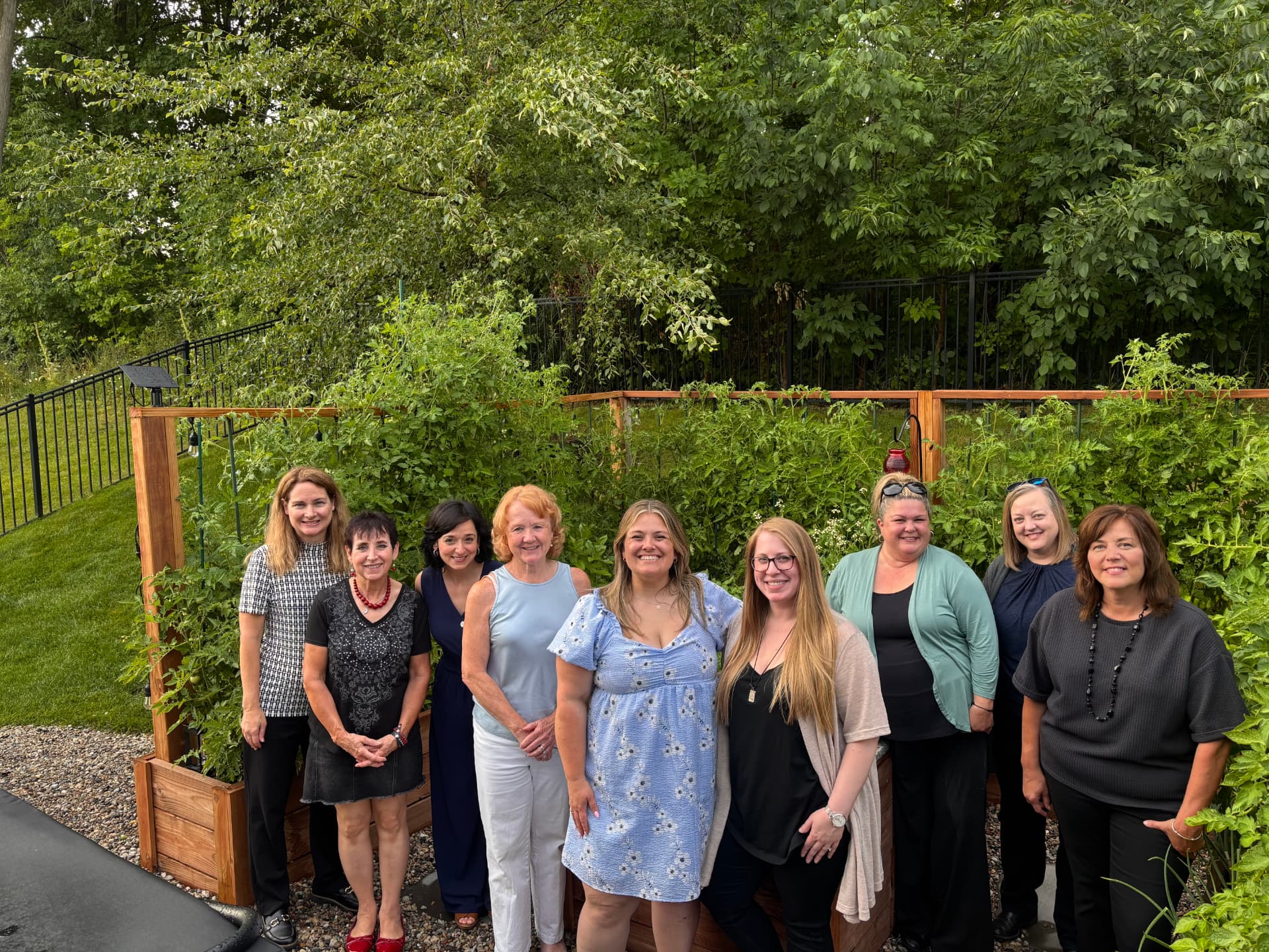 Nine guests gathered together beside the raised garden beds after a private workshop